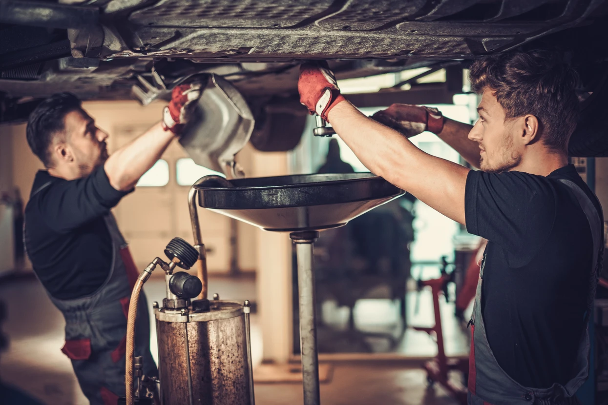 Mécanicien professionnel de la voiture changeant l'huile à moteur dans un moteur d'automobile au poste de service de réparation de maintenance dans un atelier de voiture