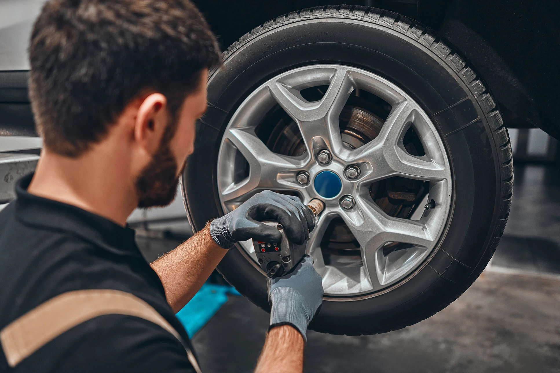 Mécanicien automobile travaillant en atelier, utilisant une clé dynamométrique électronique pour serrer les boulons d'une jante alliage