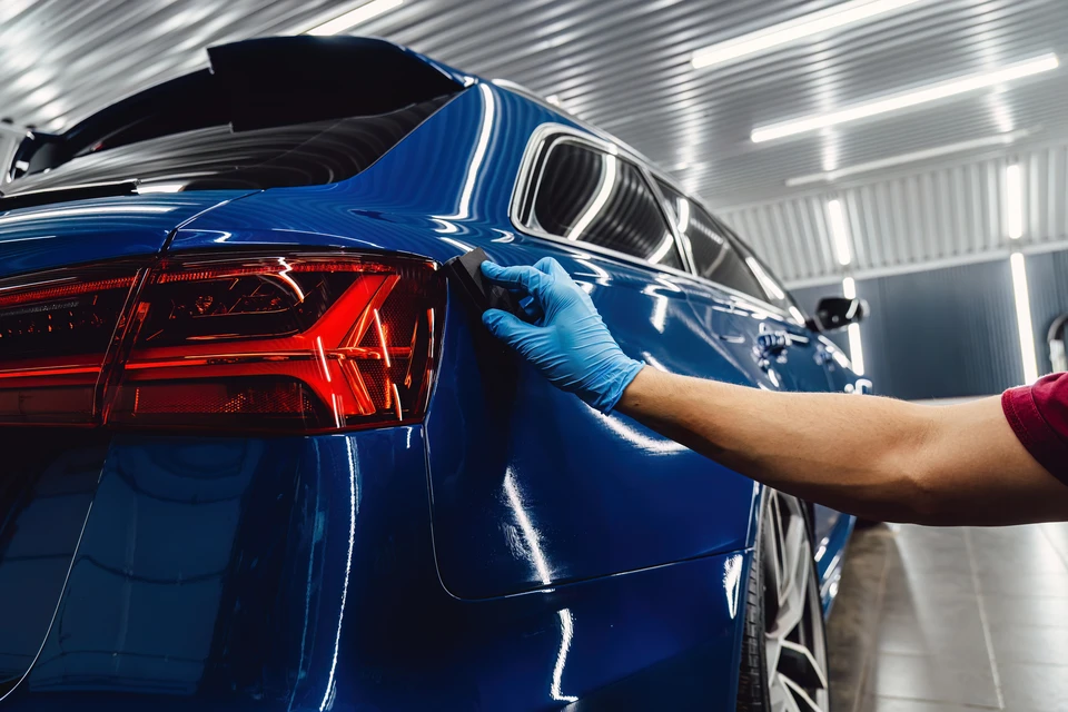 Mécanicien automobile travaillant sous un véhicule surélevé dans un garage professionnel, effectuant des réparations avec outillage spécialisé