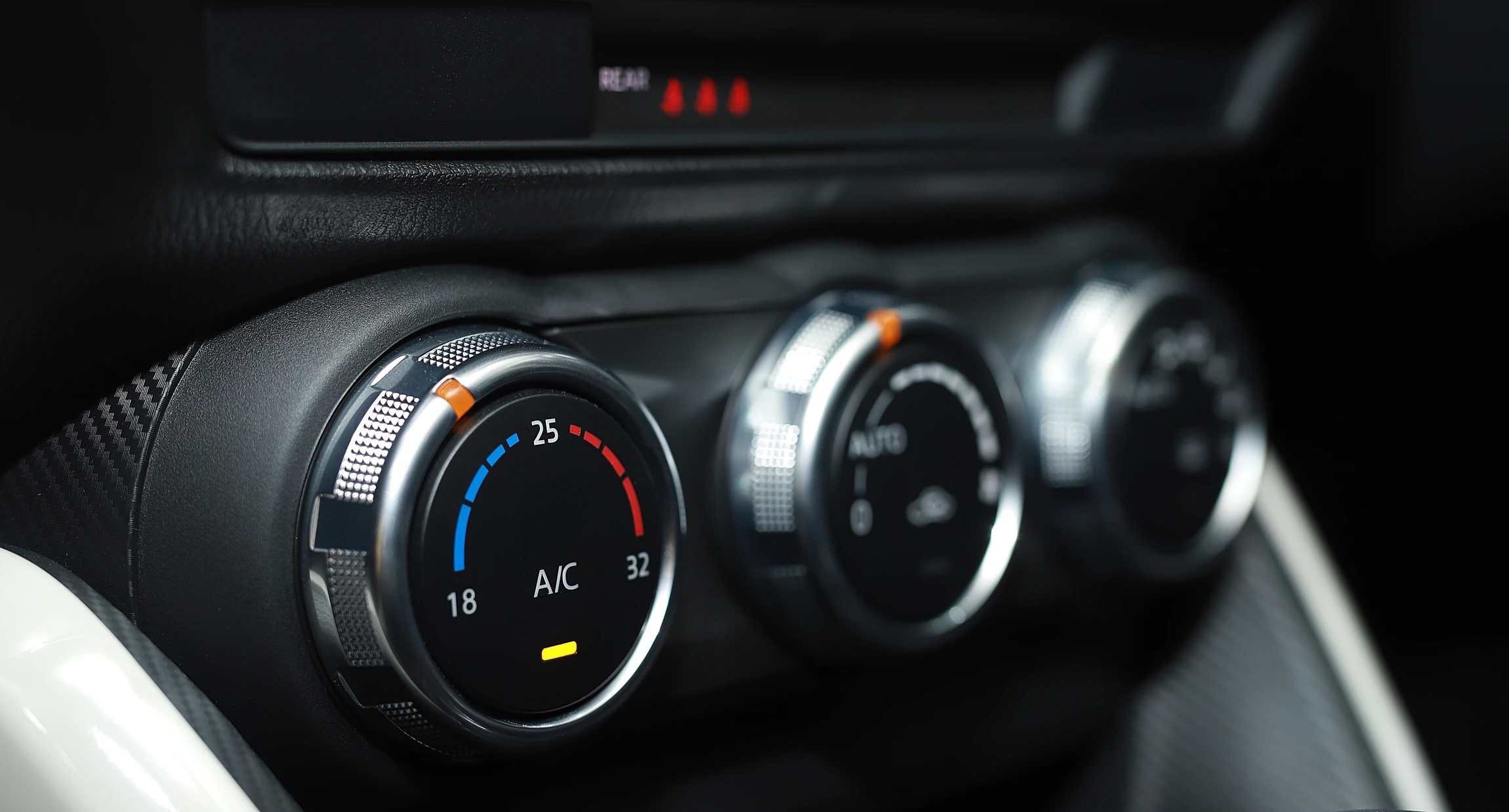 Photographie d'un technicien automobile en tenue professionnelle effectuant un diagnostic ou une maintenance sur le système de climatisation d'un véhicule en atelier. L'image montre le technicien utilisant un équipement de recharge de climatisation spécialisé connecté au véhicule, dans un atelier moderne bien éclairé. La scène doit transmettre le professionnalisme, la compétence technique et la maîtrise du service de climatisation automobile.